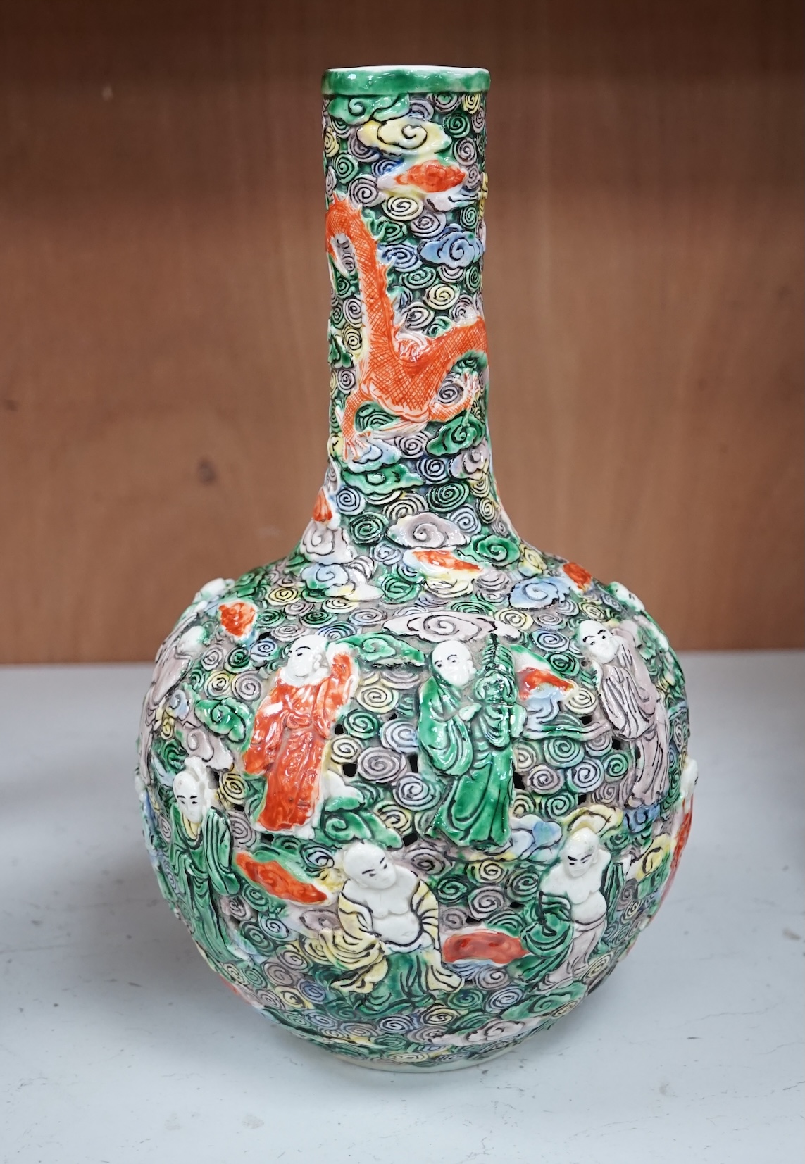 A Chinese moulded and reticulated porcelain eighteen luohan bottle vase, early 20th century, 34cm high. Condition - good